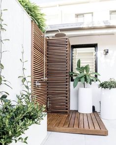 an outdoor shower with wooden slats and planters on the side of the building