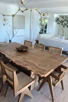 a wooden table with chairs around it in the middle of a living room filled with furniture