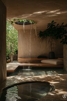 an indoor spa with water flowing from the ceiling and plants growing on the wall above it