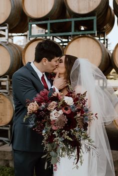 a bride and groom kissing in front of wine barrels