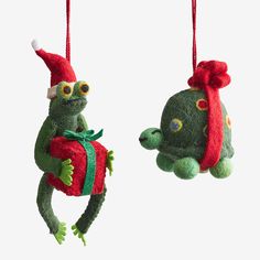 two christmas ornaments hanging from strings, one with a turtle on it's back