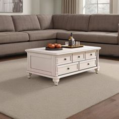 a white coffee table sitting on top of a rug in front of a gray couch