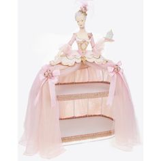 a doll is sitting on top of a three tiered display case with pink ribbons and bows