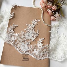 an open notebook with white lace and flowers on it, next to a bouquet of flowers