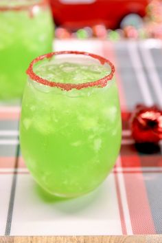 two glasses filled with green liquid sitting on top of a checkered tablecloth covered table