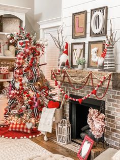 a christmas tree decorated with red, white and black ribbons in front of a fireplace