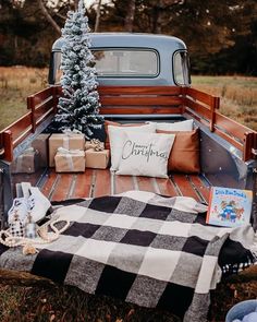 a christmas tree sitting in the back of an old pickup truck with presents on it