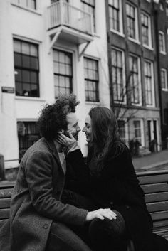 two women are sitting on a bench and one is kissing the other's cheek