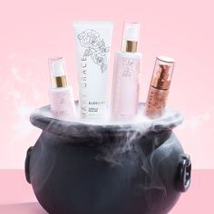 a black pot filled with lots of different types of skin care products on top of a pink background