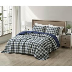 a bed with blue and white plaid comforter on top of it in a room