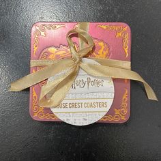 a harry potter house crest coaster with a ribbon tied around it's edge on a black surface