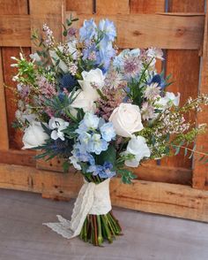 a bouquet of blue and white flowers in front of a wooden door with lace on it