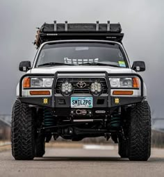 the front end of a white toyota truck with its lights on and four wheel drive