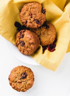 three muffins in a white bowl on a yellow napkin