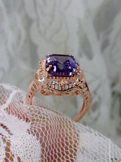 Natural Purple Amethyst Rose Gold plated Sterling Silver RingPicture Frame Design#D227 Inspired by Victorian era designs, this is a lovely reproduction ring. This lovely filigree handcrafted sterling silver ring is overlaid with rose gold plating. This flawless 5 carat Natural Purple Amethyst is 11mm x 9mm. The ring is 11/16" (17.5mm) North to South on the finger. The inside of the band is marked 925 for sterling silver. Notice the beautiful daisies on the outside of the setting and band. There Heirloom Amethyst Rings With Intricate Design, Amethyst Filigree Ring For Anniversary, Amethyst Rings With Intricate Design For Wedding, Victorian Amethyst Jewelry For Weddings, Victorian Amethyst Wedding Jewelry, Elegant Purple Amethyst Ring With Intricate Design, Heirloom Amethyst Ring With Filigree For Anniversary, Heirloom Amethyst Ring For Anniversary With Intricate Design, Heirloom Amethyst Filigree Ring For Anniversary