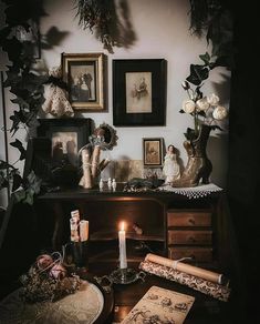 an old fashioned desk with candles and pictures on the wall next to it in a dark room