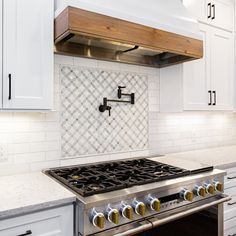 a stove top oven sitting inside of a kitchen next to white cabinets and counter tops