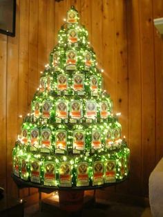 a christmas tree made out of beer bottles is lit up with green lights in the shape of a pyramid