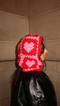 a woman wearing a red and white crocheted hat with a black leather jacket