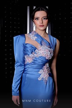 a woman in a blue dress with flowers on it's neck and shoulders, posing for the camera