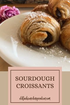 two croissants sitting on top of a white plate covered in powdered sugar