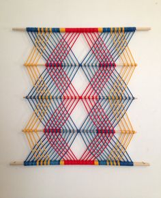 a wall hanging made out of sticks and yarn