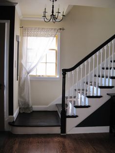 an empty room with stairs and a chandelier hanging from the ceiling next to a window