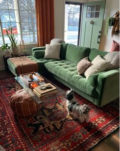 a living room with green couches and rugs on the floor in front of large windows