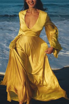 a woman in a yellow dress standing on the beach