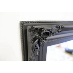 an ornate black framed mirror hanging on the wall