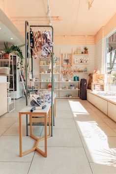 the inside of a clothing store with lots of items on shelves and tables in front of them