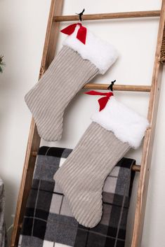 two christmas stockings hanging on a ladder next to a plaid blanket and potted plant