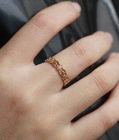 a close up of a person's hand wearing a gold ring with flowers on it