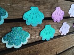 paper flowers are hung on a clothes line with glitters and blue, pink, purple, and green colors