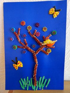 an art project made out of paper and plastic beads on a blue background with a tree