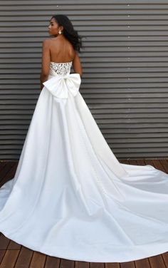 a woman in a white wedding dress standing on a wooden floor with her back to the camera