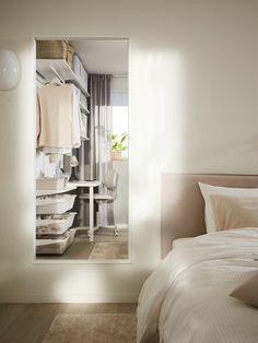 a white bed sitting next to a mirror in a bedroom