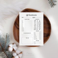 a wooden plate with a paper on top of it next to cotton balls and a pine branch