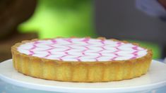 there is a small cake on top of a plate with pink and white icing