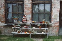 an old brick building with potted plants on the windows sill and wooden bench