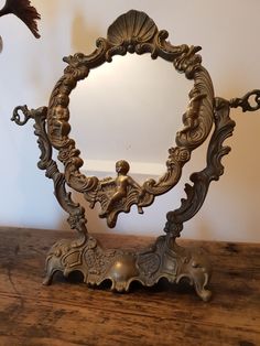 an ornate mirror sitting on top of a wooden table next to a bird flying over it