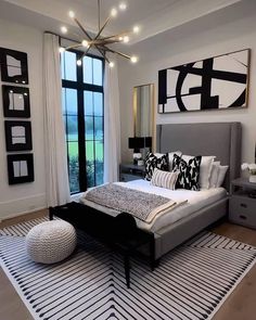 a modern bedroom with black and white decor on the walls, large windows, and a bed in front of a window