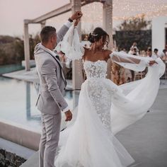 a bride and groom dancing by the pool