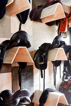 many different types of saddles are hanging on the wall