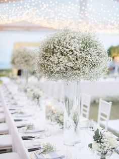 the table is set with white flowers and place settings for guests to sit down at