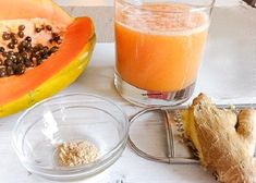 there is a glass of juice next to some fruits and vegetables on the counter top