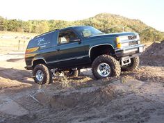 a large green truck parked on top of a dirt hill