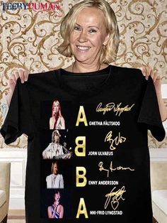 a woman holding up a t - shirt with the names of some famous people on it