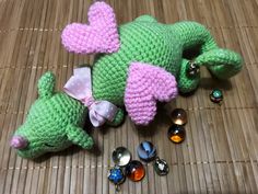 two crocheted stuffed animals laying next to each other on a bamboo mat with beads