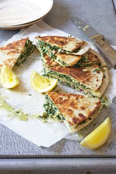 a plate topped with cut in half quesadillas next to a knife and fork